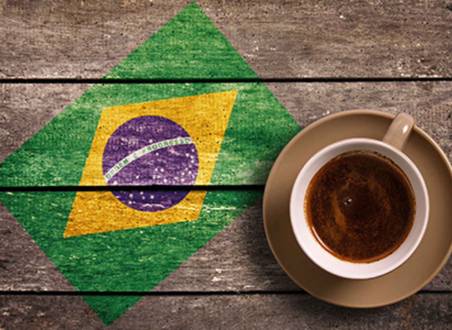 Kopp kaffe på ett träbord med den brasilianska flaggan målad på bordet