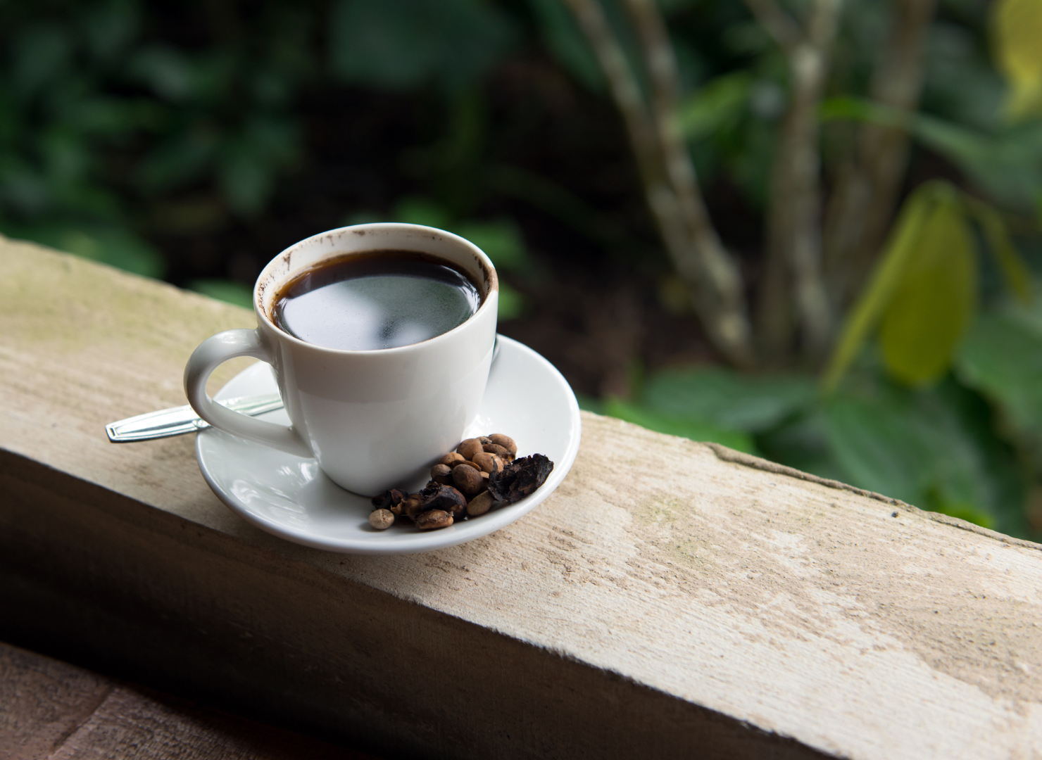 Svart kaffe i en vit kopp på en träbjälke