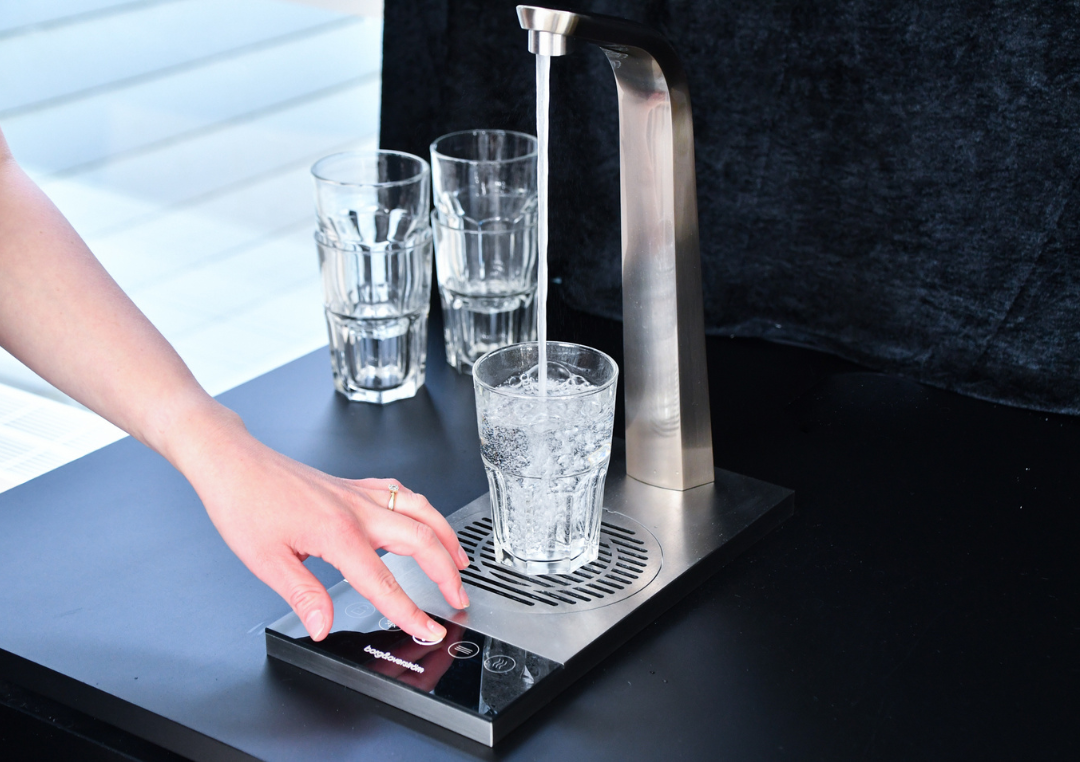 Vatten hälls i ett glas från en vattenautomat