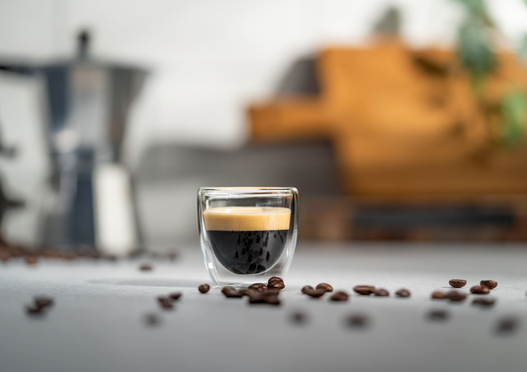 Kopp espresso på ett bord med bönor runtomkring