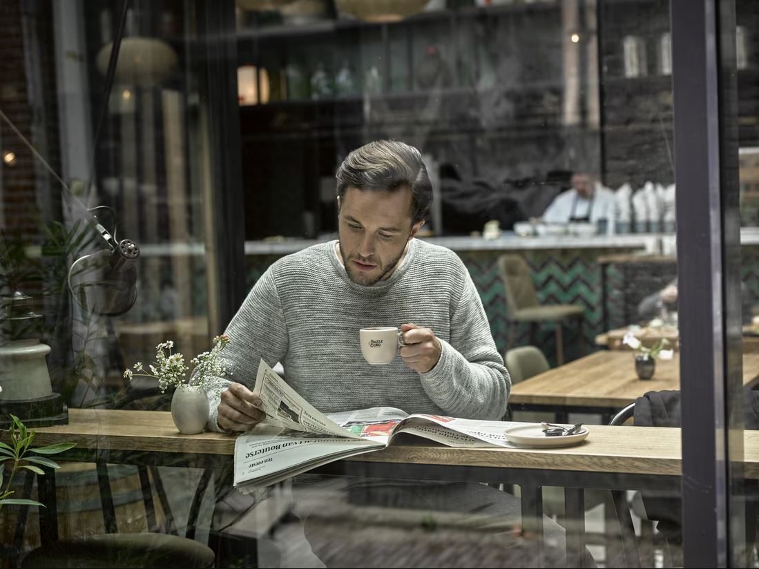 Man drinking coffee and reading newspaper