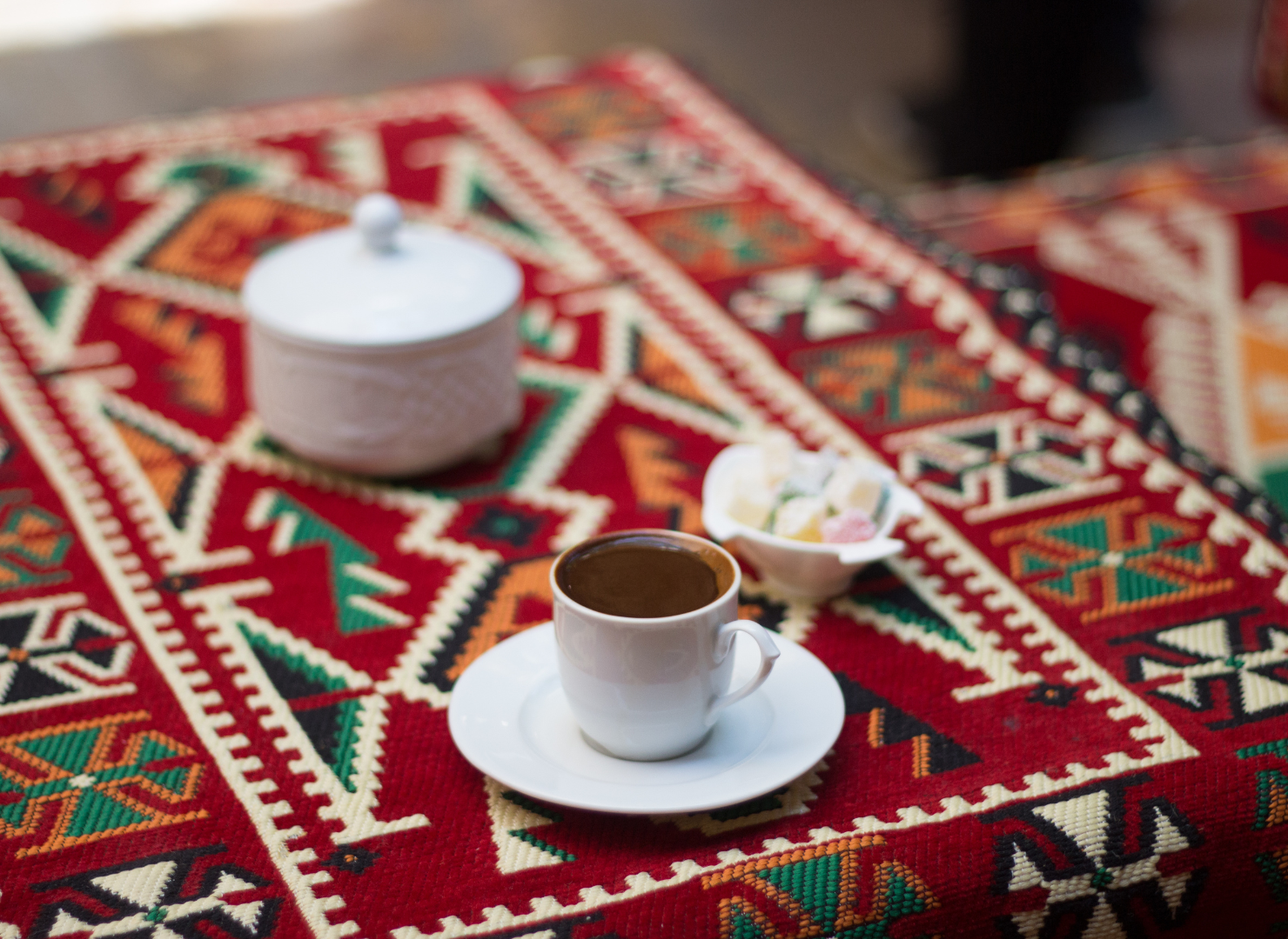 Svart kaffe i vit kopp på ett bord med röd duk
