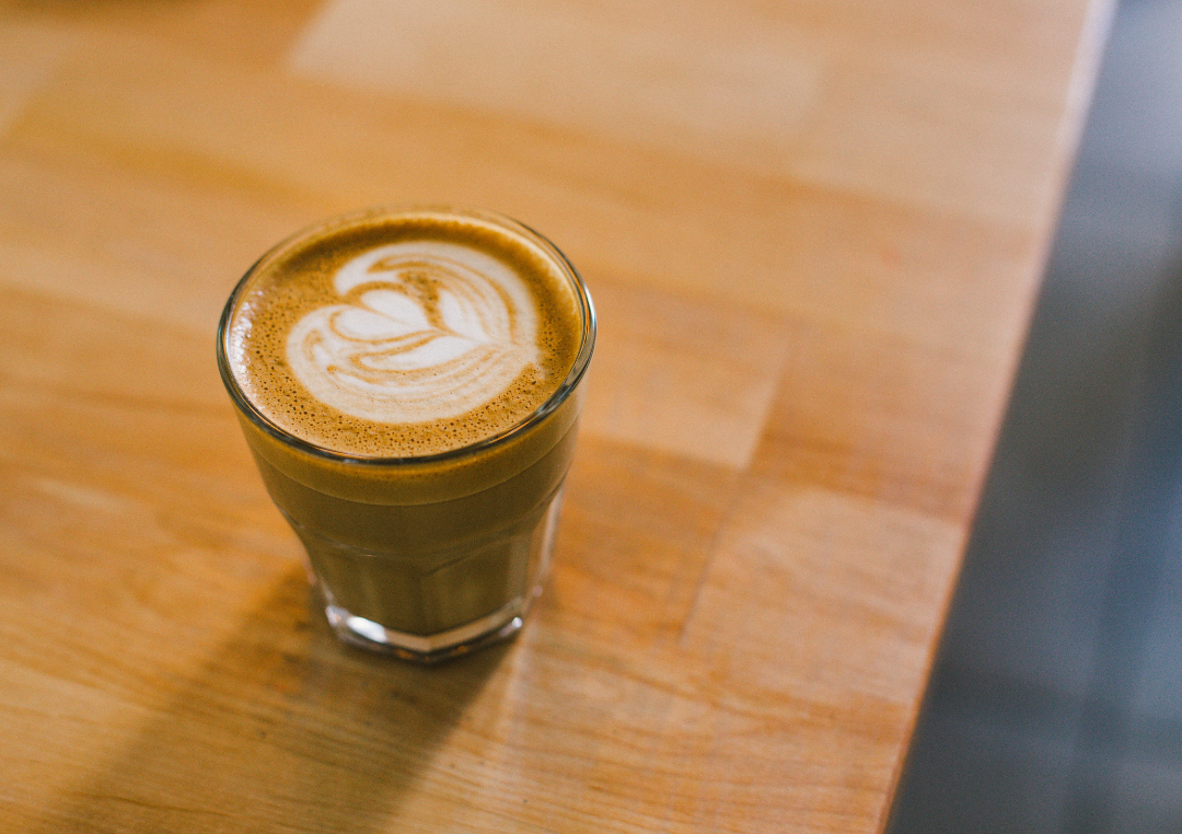 Flat white i en glasmugg på ett träbord