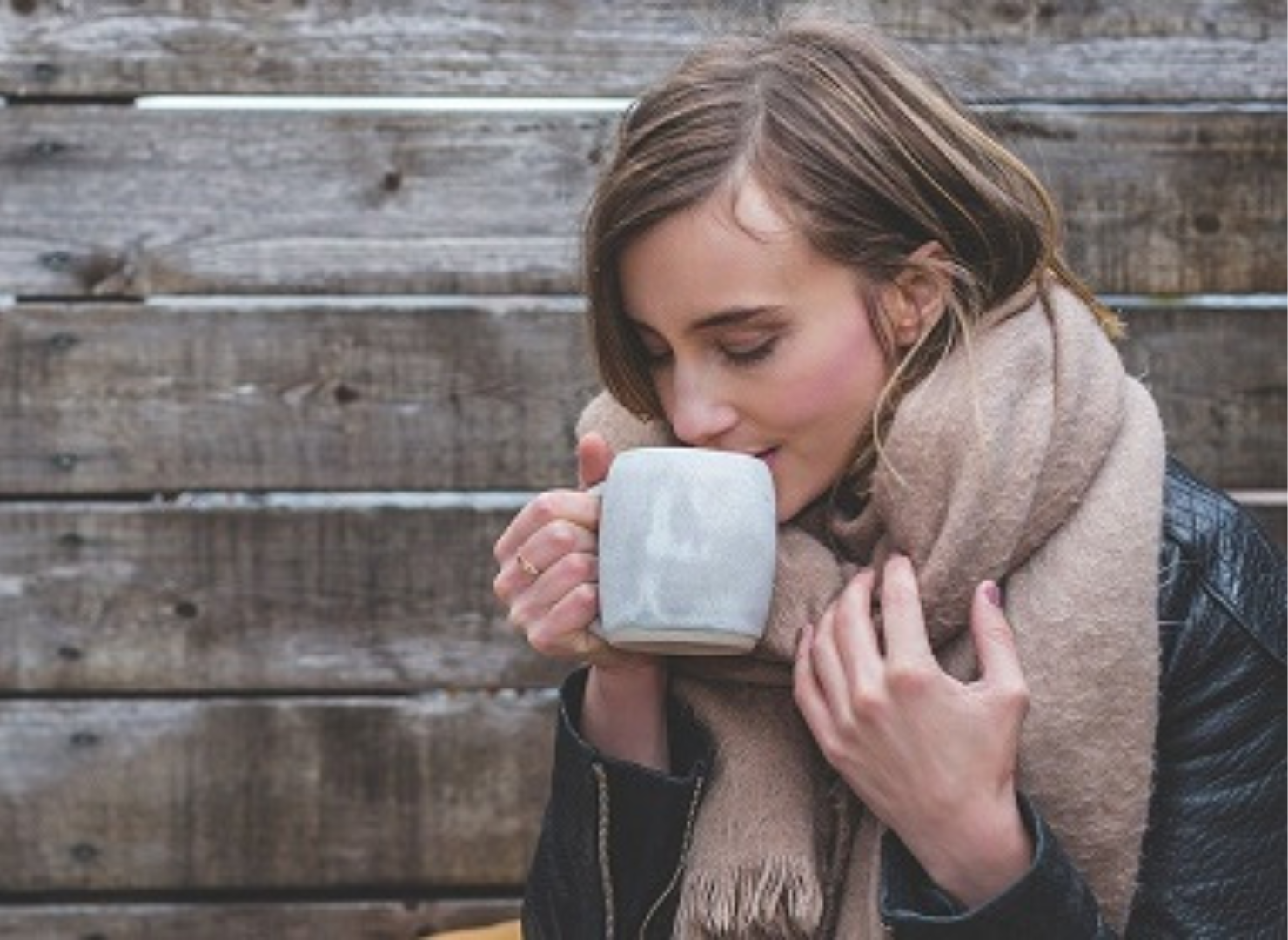 Kvinna som står utanför med en kopp kaffe och tar en klunk