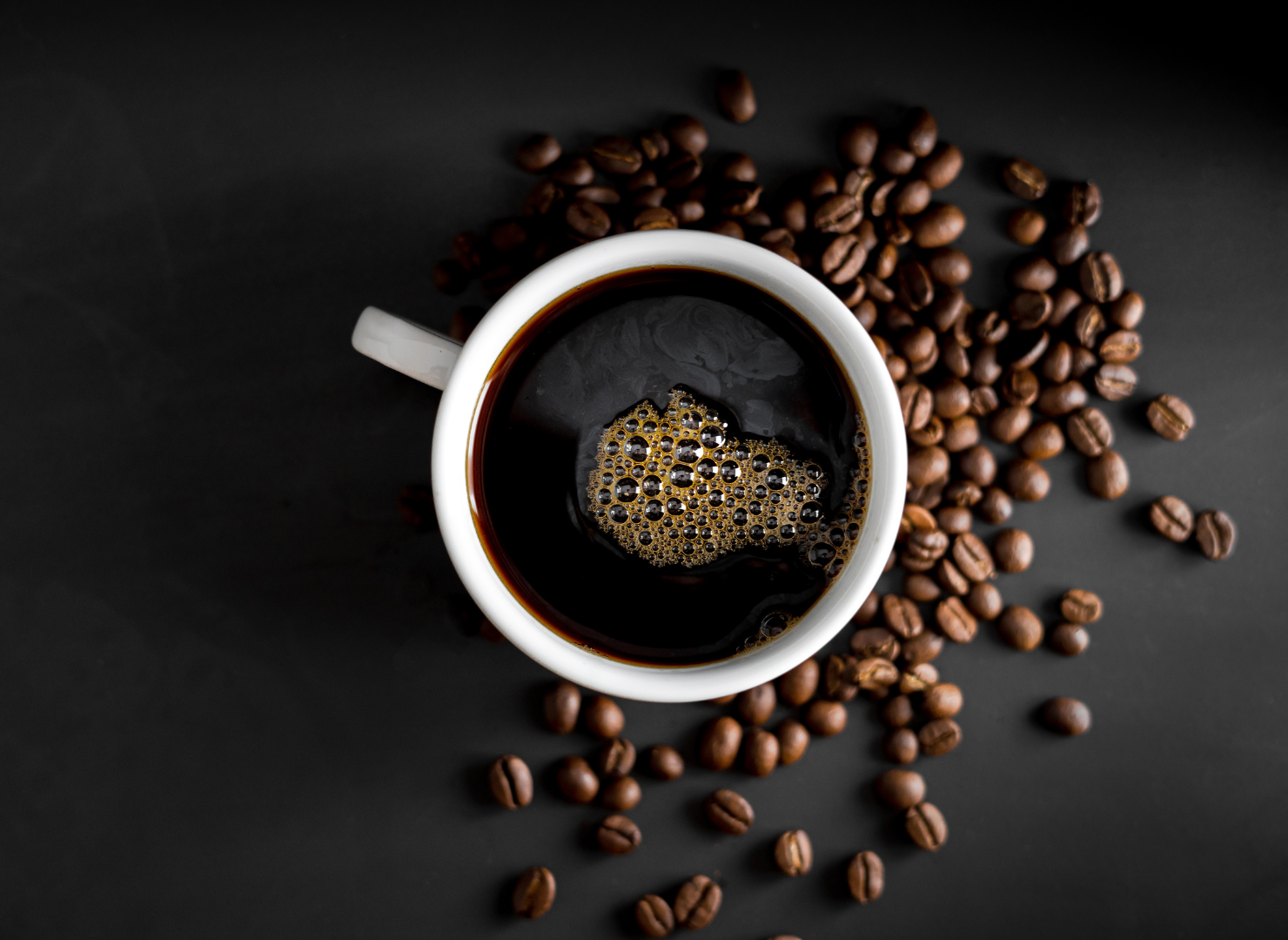 kopp svart kaffe stående ovanpå kaffebönor